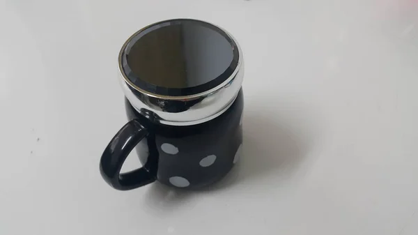 Beautiful coffee black mug with white dots over white floor with black lid on it — Stock Photo, Image