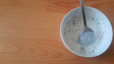 Gümüş kaşıkla beyaz seramik kasede sade lor veya yoğurt veya dahi yakın