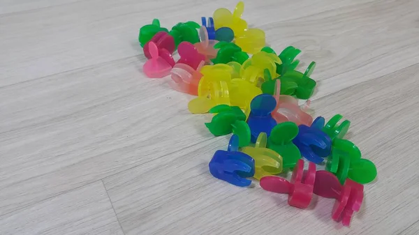 Una gran cantidad de pequeños clips de sujeción de colores colocados en un piso de madera —  Fotos de Stock