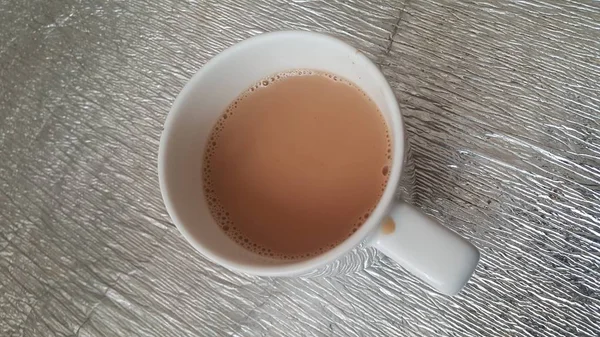 Top vy av mjölk svart te i en keramisk kopp placerad över en matta plåt — Stockfoto