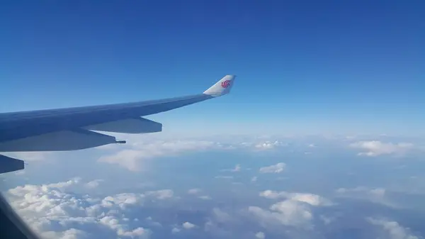 Vista aérea desde la ventana del avión de hermosas nubes y cielo azul — Foto de Stock