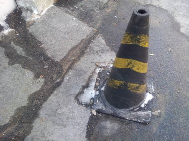 Gri asfalt üzerinde sarı ve gri şeritler ile trafik koni, yol inşaat uyarı koni