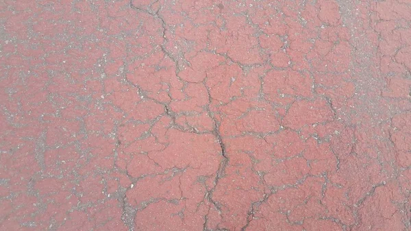 Red colored damaged road or paved pathway with crackes