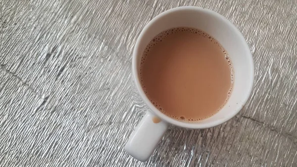 Vista superior del té negro de leche en una taza de cerámica colocada sobre una hoja de estera — Foto de Stock