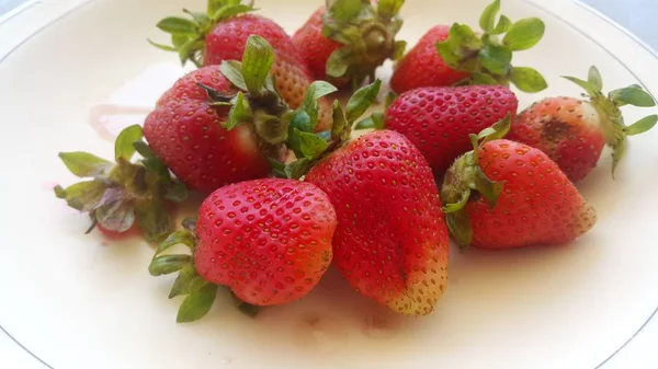Topputsikt över färska jordgubbar i plåt på rustik vit trä bakgrund. — Stockfoto