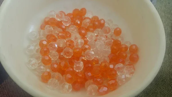 Perles ou pierres précieuses brillantes, transparentes, de couleur orange dans un bol — Photo