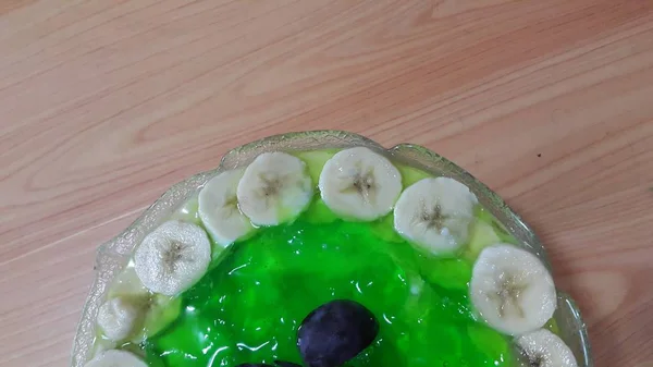 Cremosa gustosa gelatina verde dolce con fette di banana stratificate sulla superficie — Foto Stock