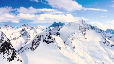 Karlı beyaz dağların arkasındaki gökyüzünde uçan beyaz bulutların zaman atlamalı görünümü. Geniş gün ışığında güneşli bir günde uçan beyaz bulutlar.