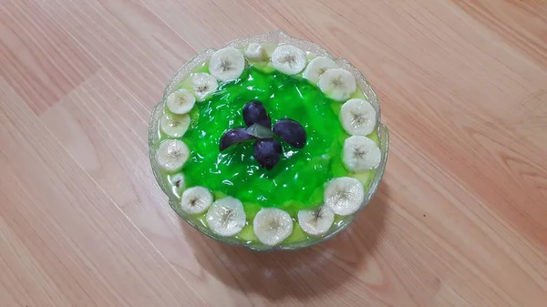 Kremowy smaczny słodki zielony galaretka z plasterkami bananów warstwowych na powierzchni — Zdjęcie stockowe