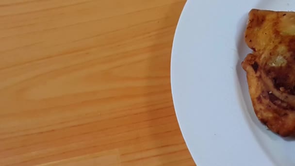 Primer plano de deliciosos pasteles caseros de samosa picantes y crujientes colocados en un plato de cerámica blanca en el suelo de madera — Vídeo de stock