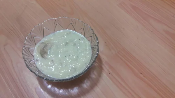 Солодкий білий рисовий пудинг у скляній мисці з банановими скибочками, розкладеними на поверхні — стокове фото