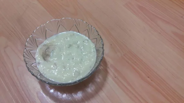 Sweet white rice pudding in a glass bowl with banana slices layered on surface — Stock Photo, Image