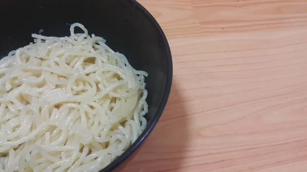 Vista ravvicinata di tagliatelle vorticose o spaghetti in una ciotola sul pavimento in legno — Foto Stock