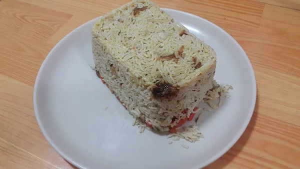 Primer plano de pastel de arroz blanco congelado en un plato blanco sobre piso de madera — Foto de Stock