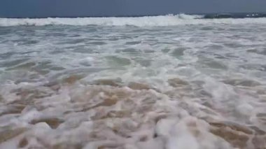 Okyanus dalgaları kumlu kıyıüzerinde ileri geri hareket ediyor. Yaz aylarında güneş ışığı üzerinde plaj denizi görünümü. 