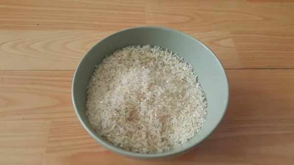 Atas close-up melihat tumpukan beras dalam mangkuk keramik ditempatkan di atas lantai kayu — Stok Foto