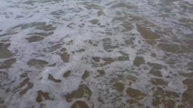Okyanus dalgaları kumlu kıyıüzerinde ileri geri hareket ediyor. Yaz aylarında güneş ışığı üzerinde plaj denizi görünümü. 