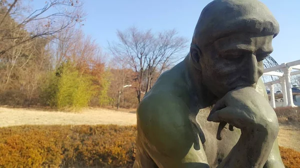 Düşünür Auguste Rodin'in yeşil heykeli, bir kayanın üzerinde çıplak ayarı — Stok fotoğraf