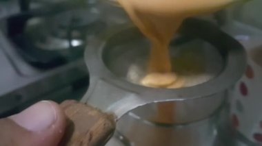 Süt çayını Chinois ya da metal elek ile süzmek. Çaydanlıktan bir fincana sütlü çay dolduruyorum..