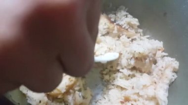 Plastik kaşıkla tavada pilav pişirip karıştırmak. Evde yemek için beyaz pirinç yemeği hazırlıyorum.