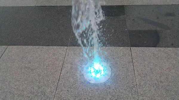 Fonte de água clara bonita e colorida sobre piso de concreto — Fotografia de Stock