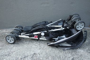 Siyah renkli bebek arabası ve kafa örtüsü. Bebek arabasının arka planı beton.