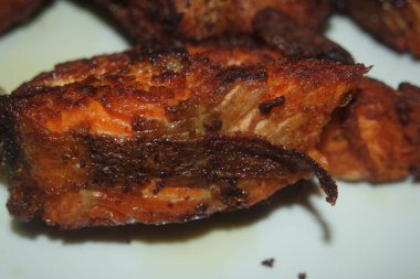 Beyaz arka planda kızarmış balık filetosunun baharatlı ve çıtır çıtır barbeküsü. Sağlıklı beslenme için ev yapımı alabalık bifteği..