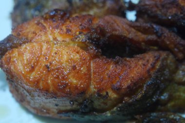 Beyaz arka planda kızarmış balık filetosunun baharatlı ve çıtır çıtır barbeküsü. Sağlıklı beslenme için ev yapımı alabalık bifteği..