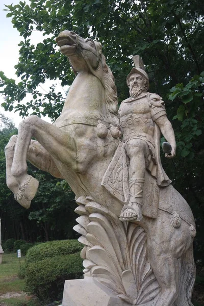 Statue made of white stone marble of an ancient famous soldier riding on the horse- White marble statue of an ancient man holding a scroll and riding a horse