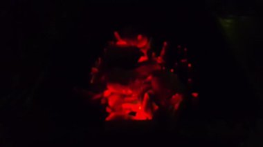 Barbekü ızgarasında yanan kömürlere yakın çekim. Kömür yanmaya başladı. Metal ızgarada bir akşam parlayan kömürün yakın çekimi