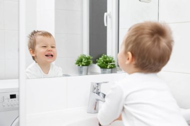 Yüzünü yıkamak için öğrenme nasıl banyo aynası içinde şirin yürümeye başlayan çocuk