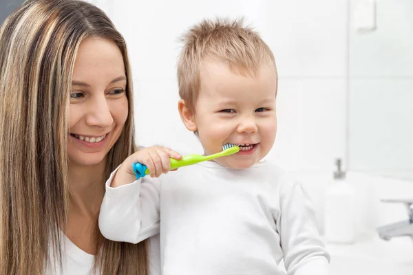 快乐的母亲教她的儿子如何在卫生间里刷牙 — 图库照片#