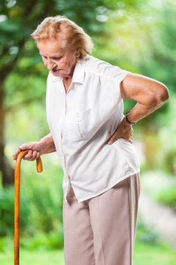Yaşlı kadın açık havada bel ağrısı ile