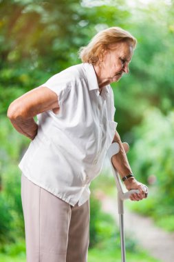 Yaşlı kadın açık havada bel ağrısı ile