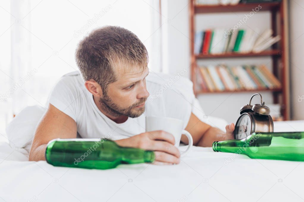 Young handsome man in bed the morning after night out drinking