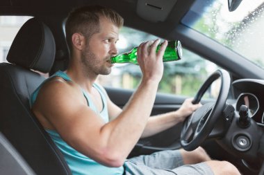 Sarhoş sürücü direksiyon başında içki içiyor.