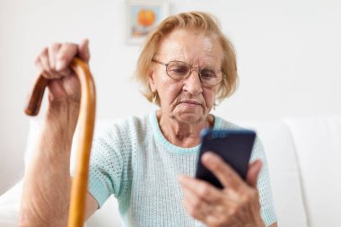 Yaşlı kadın ile gözlük ve bir cep telefonu kullanarak kamışı