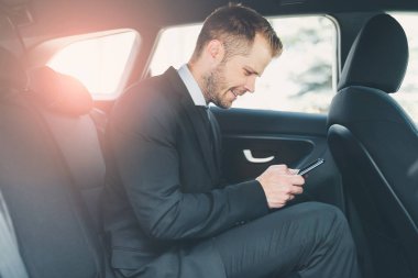 Bir cep telefonu kullanarak araba arkasında oturan çift iş adamı