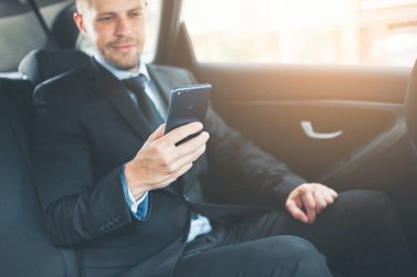 Bir cep telefonu kullanarak araba arkasında oturan çift iş adamı