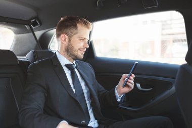 Bir cep telefonu kullanarak araba arkasında oturan çift iş adamı