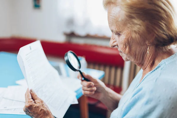 老妇人看她的公用事业账单和文书工作 — 图库照片
