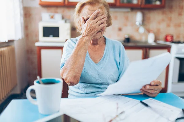 Elderly woman looking at her utility bills and paperwork