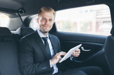 Dijital tablet kullanma araba arkasında oturan çift iş adamı