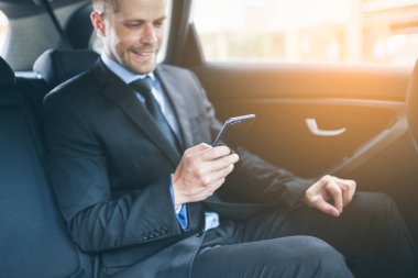 Bir cep telefonu kullanarak araba arkasında oturan çift iş adamı