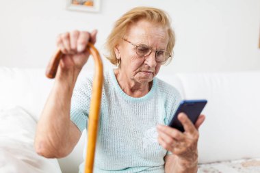 Yaşlı kadın ile gözlük ve bir cep telefonu kullanarak kamışı