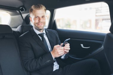 Bir cep telefonu kullanarak araba arkasında oturan çift iş adamı