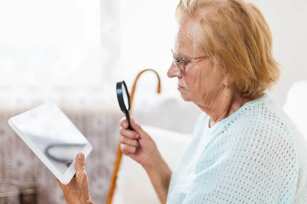Starsza Kobieta Okularach Lupie Pomocą Nowoczesnej Tabletu Cyfrowego — Zdjęcie stockowe