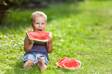 Outdoords oturan ve bir dilim karpuz yeme şirin bebek
