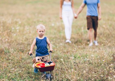 Sevimli bir çocuk ve ailesi bir engerek arabasını dışarı itiyor.
