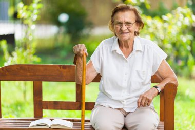 Oturma ve açık havada parkta bir bankta rahatlatıcı yaşlı kadın